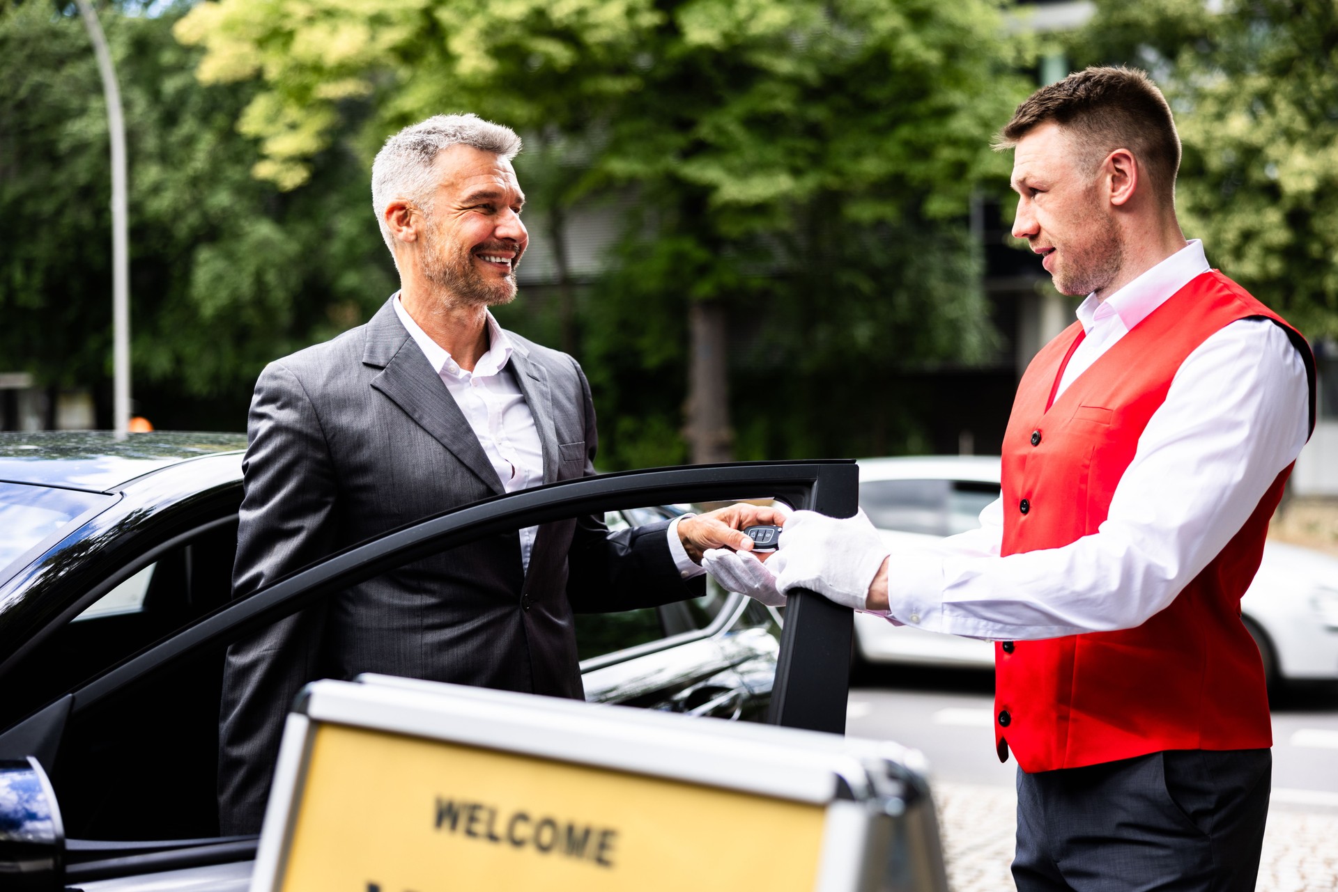 Luxury Car Rental Service: Professional Businessman Smiling as Valet Hands Over